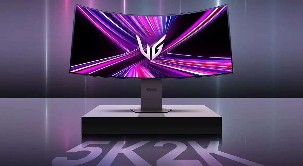 Monitor curvo LG UltraGear sobre una base gris plana, mostrando un fondo de líneas luminosas en tonos fucsia y violeta. En la superficie inferior de la imagen se refleja de forma destacada el texto '5K2K'.